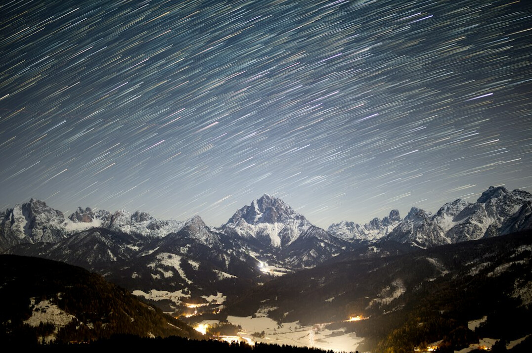 Starry night sky over snowy mountains
